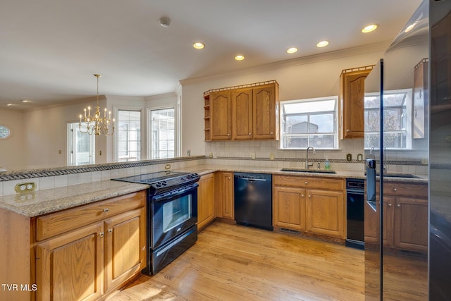 kitchen with plenty of natural light, an inviting chandelier, black appliances, and light hardwood / wood-style flooring