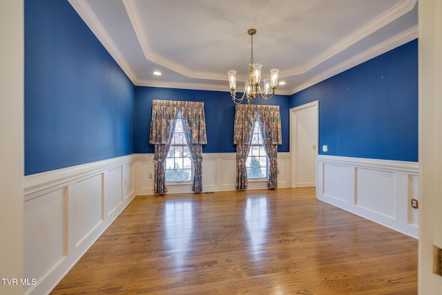 spare room featuring wood-type flooring, an inviting chandelier, and crown molding