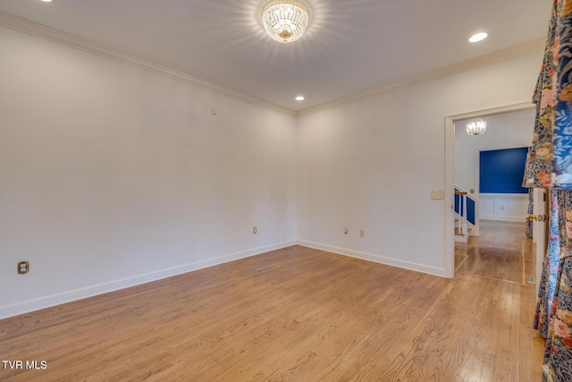 spare room with light wood-type flooring, crown molding, and a chandelier