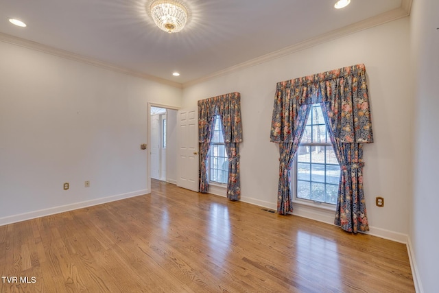 empty room featuring light wood-type flooring, crown molding, and a notable chandelier