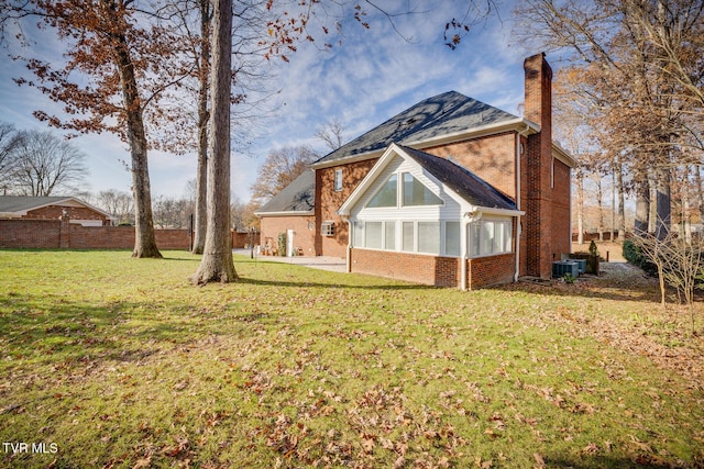 back of house with central AC unit, a lawn, and a sunroom