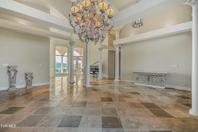 unfurnished dining area featuring a high ceiling, ornate columns, and a notable chandelier