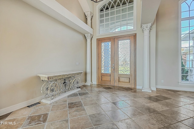 foyer entrance with french doors, decorative columns, and a high ceiling