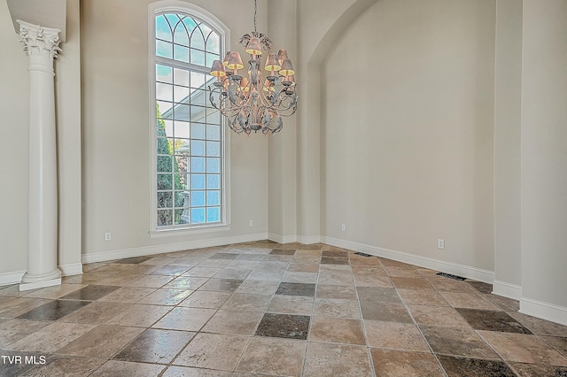 unfurnished dining area with decorative columns and a chandelier