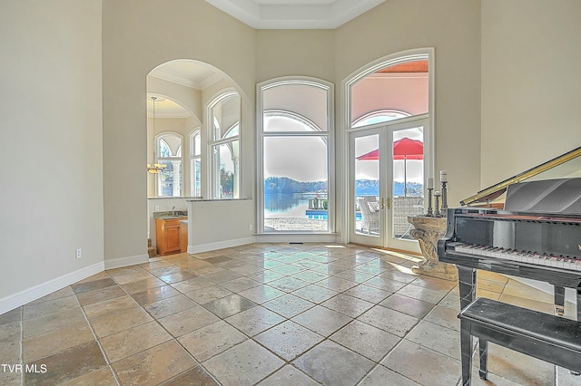 foyer featuring a towering ceiling, crown molding, and french doors