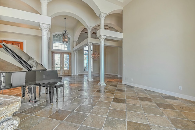 interior space featuring ornate columns, french doors, a towering ceiling, and a chandelier