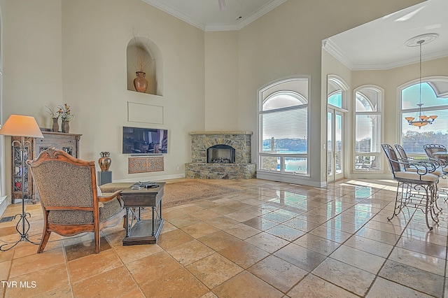 living room with a fireplace, a towering ceiling, an inviting chandelier, and crown molding