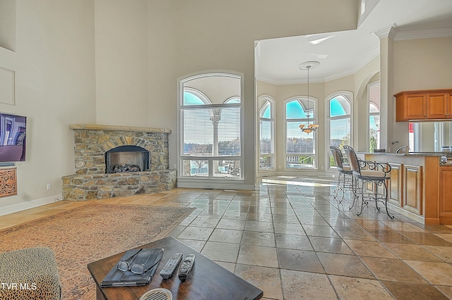 living room featuring crown molding, a fireplace, a towering ceiling, and a chandelier