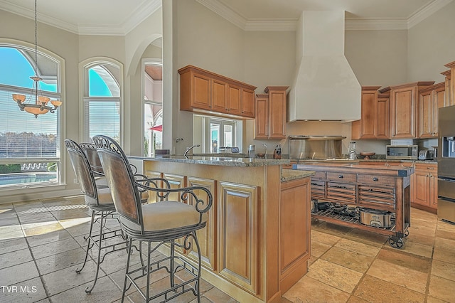 kitchen with kitchen peninsula, premium range hood, and ornamental molding