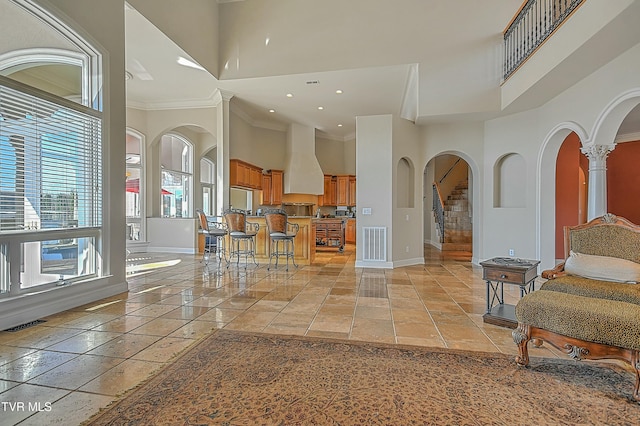 entryway featuring ornate columns, a towering ceiling, and ornamental molding