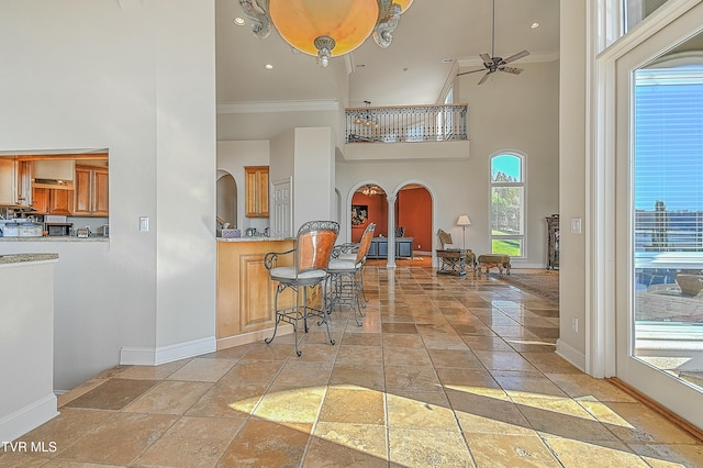 kitchen featuring a breakfast bar, ceiling fan, crown molding, and a high ceiling