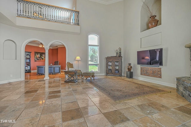 living room featuring a high ceiling, decorative columns, and crown molding