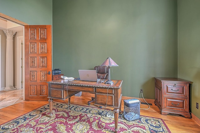 office area with decorative columns and light hardwood / wood-style floors