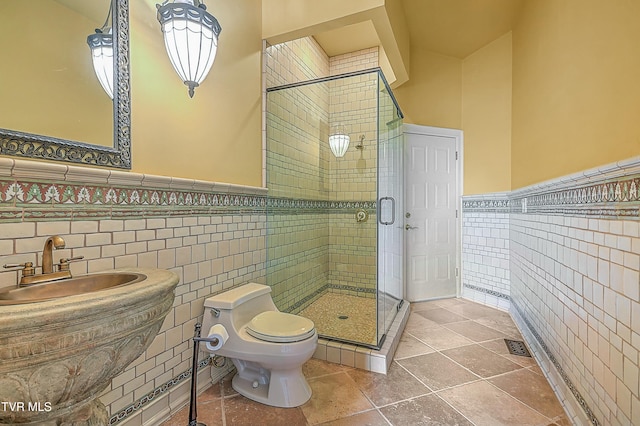 bathroom featuring sink, toilet, a shower with shower door, and tile walls