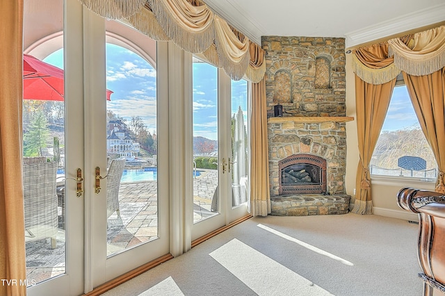 doorway featuring a fireplace, carpet floors, a wealth of natural light, and ornamental molding