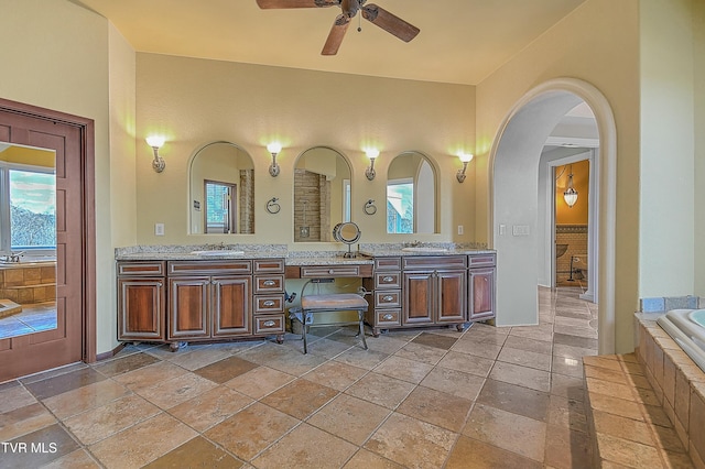 bathroom featuring vanity, tiled bath, and ceiling fan