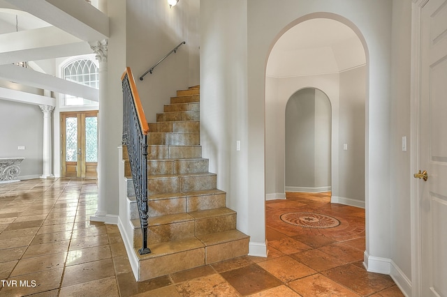 staircase featuring a towering ceiling and french doors