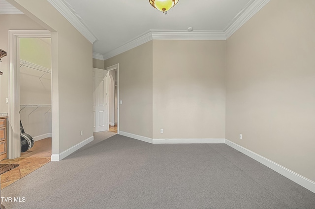 unfurnished bedroom with carpet flooring, crown molding, a closet, and a spacious closet