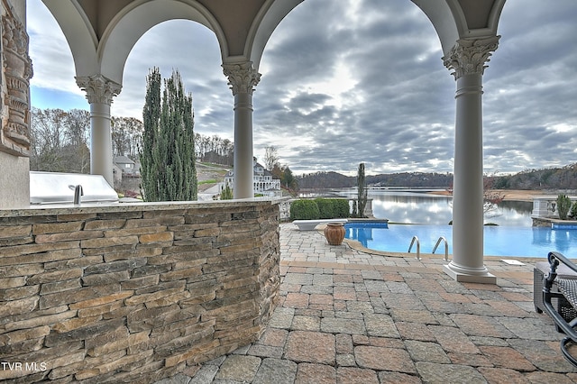 view of patio featuring a water view and exterior kitchen