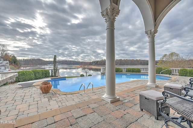 view of swimming pool featuring a patio and a water view