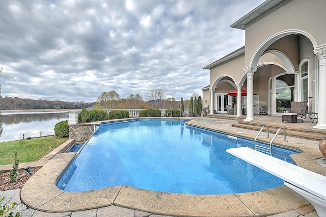 view of swimming pool with a water view, a diving board, and a patio area