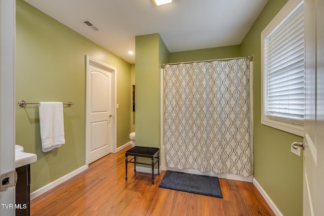 bathroom with hardwood / wood-style flooring, toilet, and walk in shower