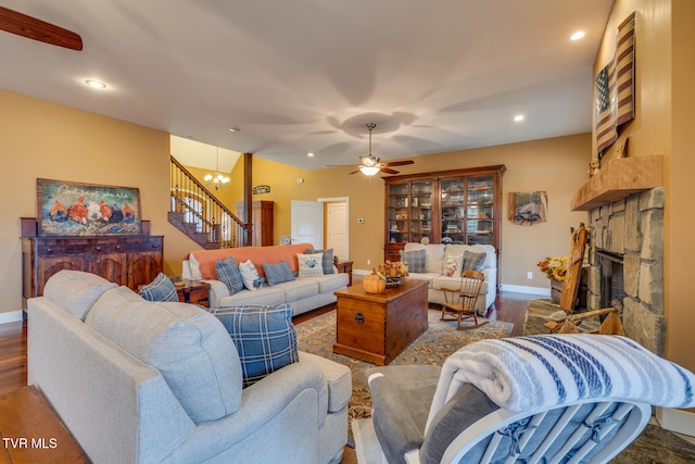 living room with ceiling fan with notable chandelier, a fireplace, and hardwood / wood-style floors