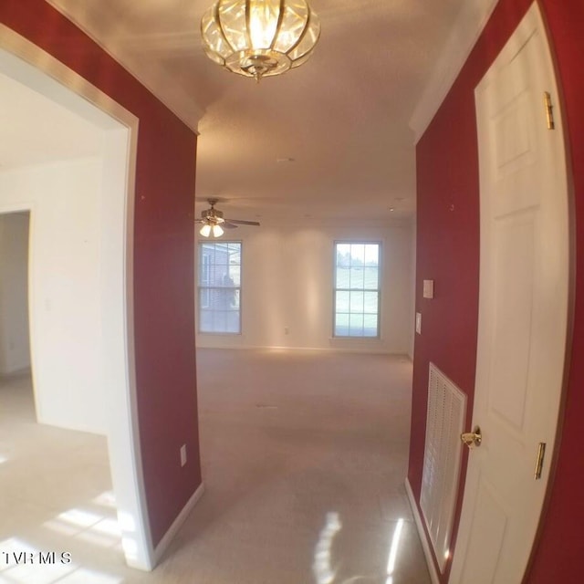 hall featuring light carpet and a chandelier