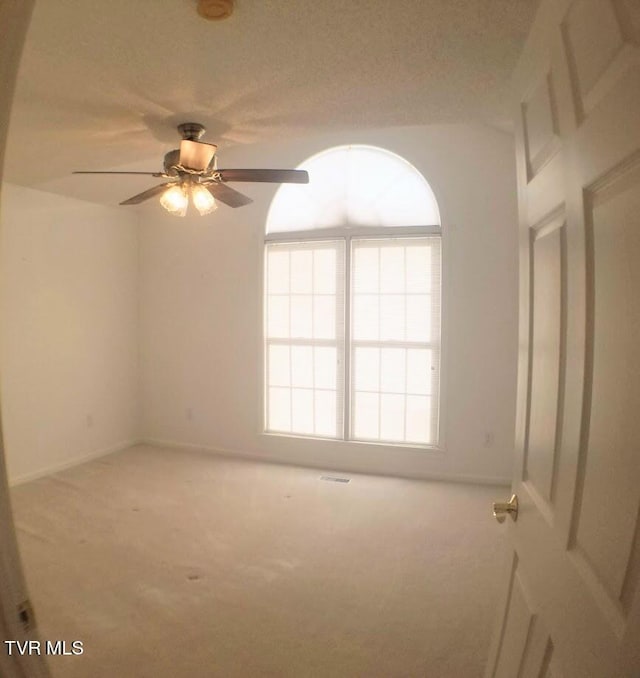 carpeted spare room with a textured ceiling and ceiling fan