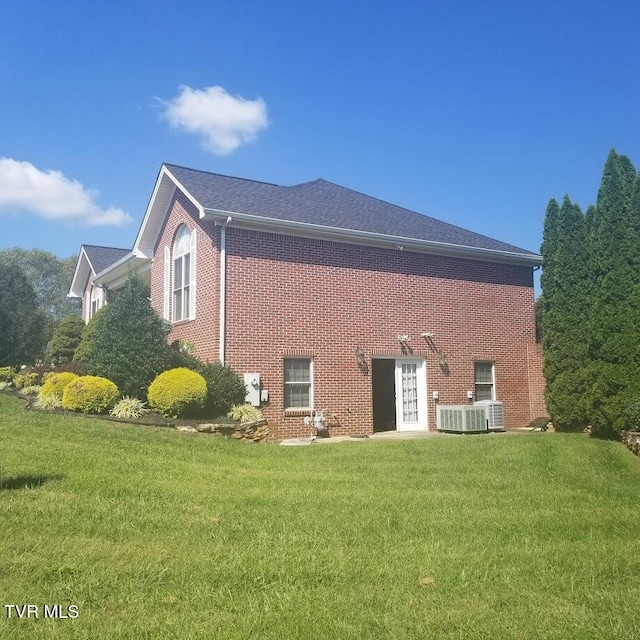 rear view of property featuring central AC and a lawn