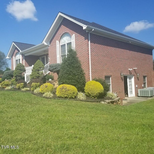 view of home's exterior with a lawn and central AC