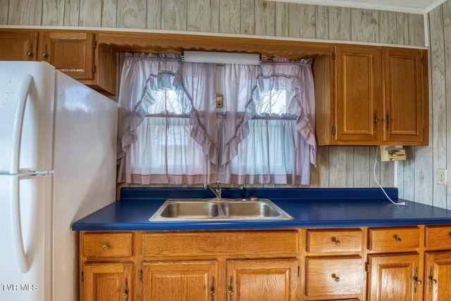 kitchen featuring wood walls, white refrigerator, and sink