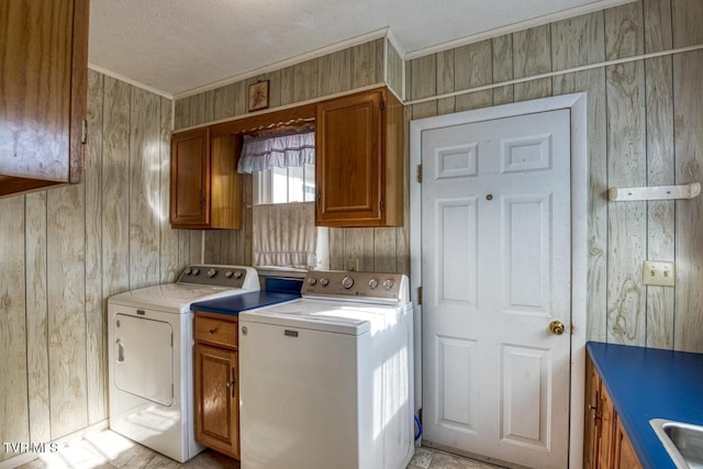 clothes washing area featuring cabinets, sink, washer and dryer, and wood walls