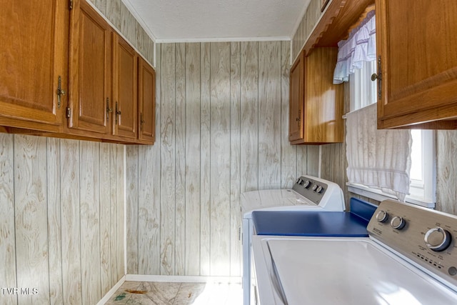 clothes washing area with washer and dryer, a textured ceiling, wooden walls, and cabinets