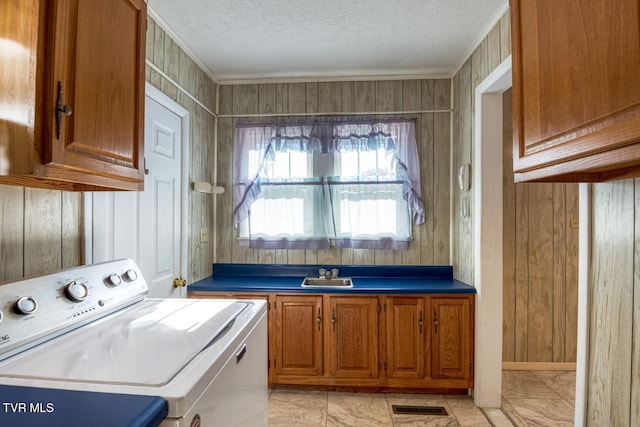 washroom with wooden walls, sink, cabinets, and a textured ceiling