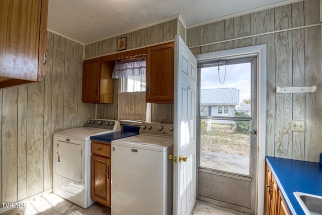 laundry room featuring separate washer and dryer, wood walls, cabinets, and a textured ceiling