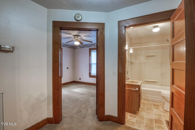 corridor featuring light carpet, sink, and a textured ceiling