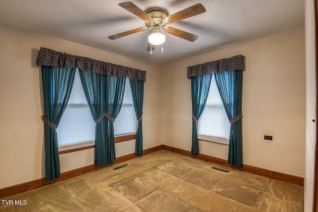 carpeted spare room with a textured ceiling and ceiling fan