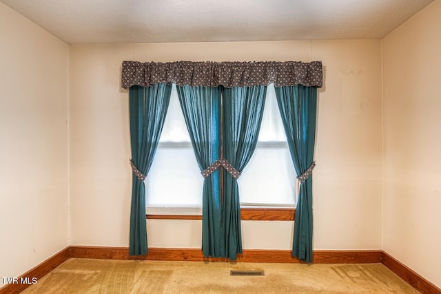 carpeted spare room with a textured ceiling