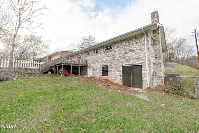 rear view of house featuring a wooden deck and a lawn