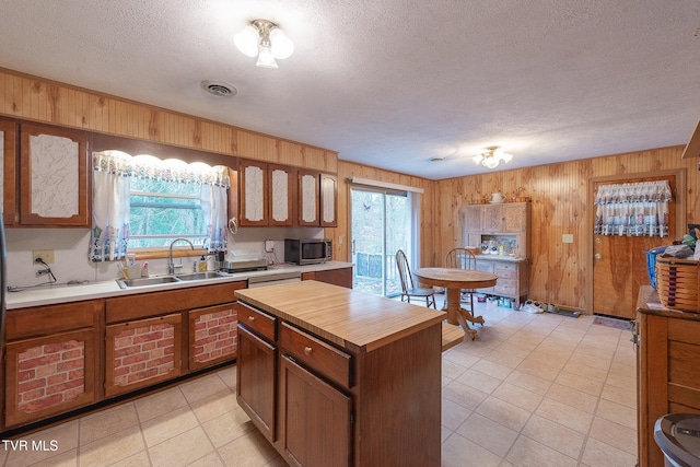 kitchen featuring wood walls, sink, a center island, and a textured ceiling