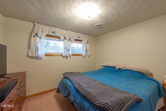 bedroom with a textured ceiling and light colored carpet