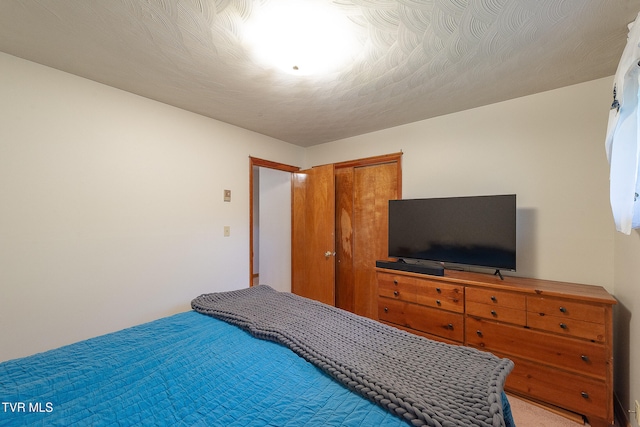 bedroom with a closet, carpet floors, and a textured ceiling