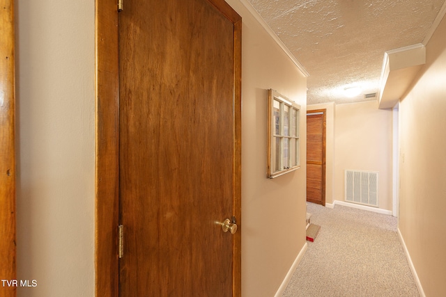 corridor featuring crown molding, light colored carpet, and a textured ceiling