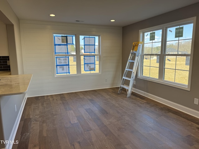 unfurnished dining area with dark wood-type flooring and wood walls