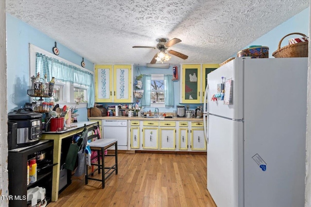 kitchen with a textured ceiling, white appliances, ceiling fan, sink, and light hardwood / wood-style floors