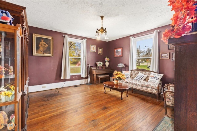 sitting room featuring a fireplace, hardwood / wood-style floors, a textured ceiling, and an inviting chandelier