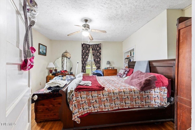 bedroom with a textured ceiling, hardwood / wood-style flooring, and ceiling fan