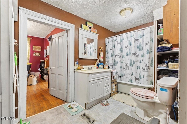 full bathroom featuring shower / bath combo, a textured ceiling, toilet, vanity, and hardwood / wood-style flooring