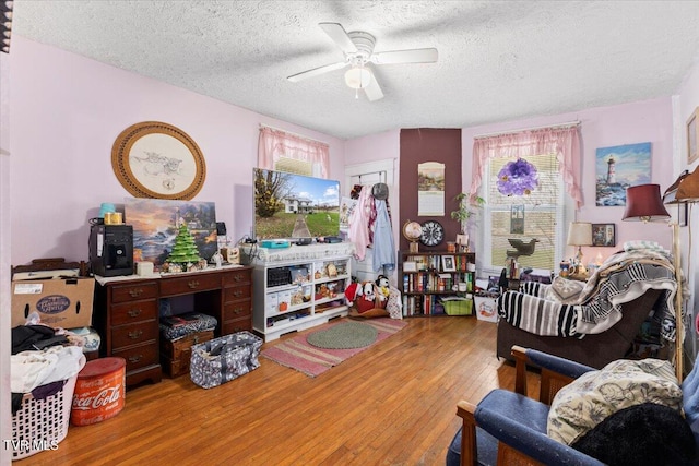 living room with hardwood / wood-style floors, ceiling fan, and a textured ceiling